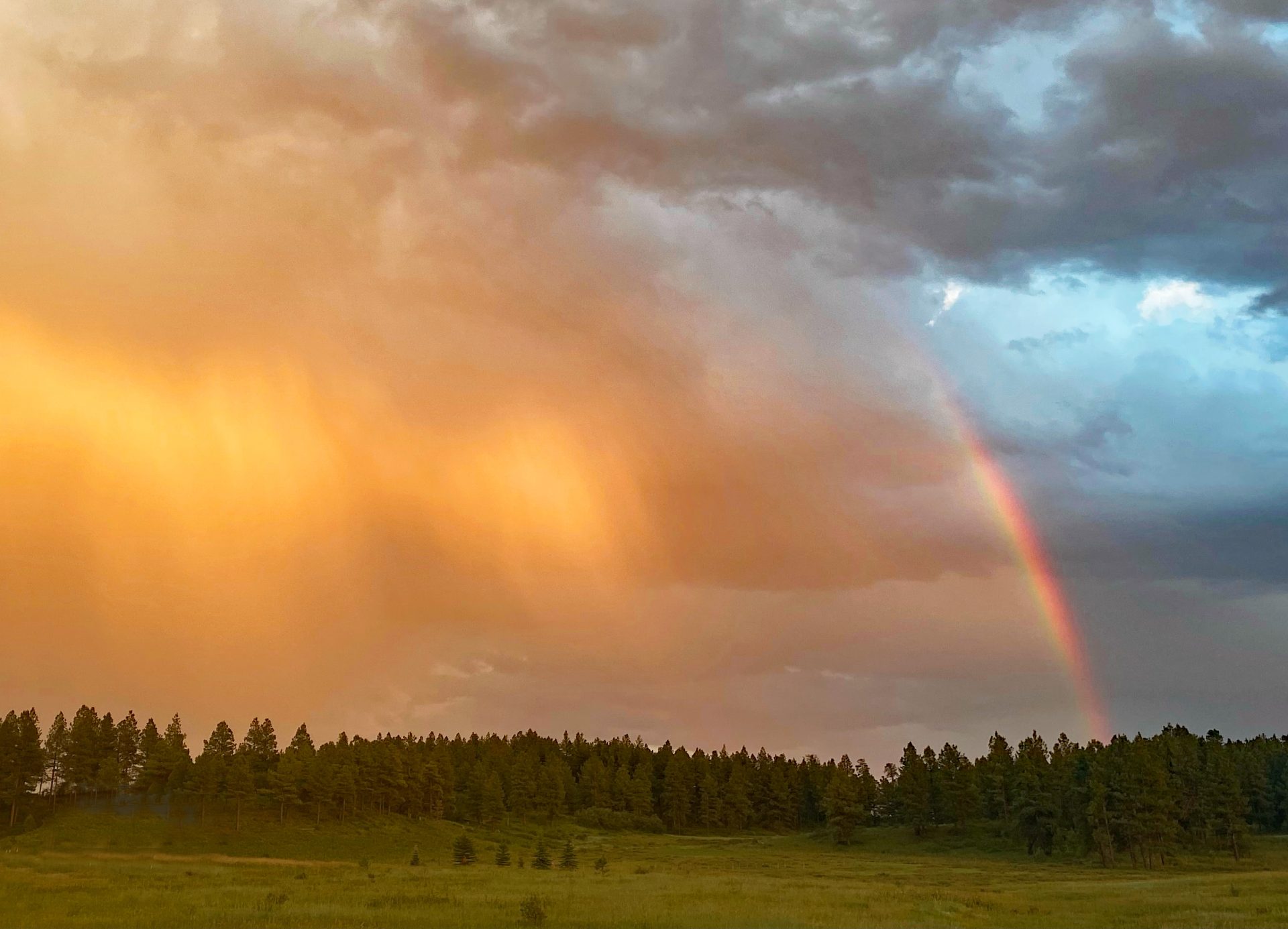 Sunset. Colors against the sky with a rainbow in the middle of the rain shaft.